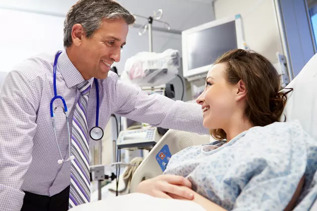 Laid Down Smiling Female Patient Talking To Male Consultant In Emergency Room
